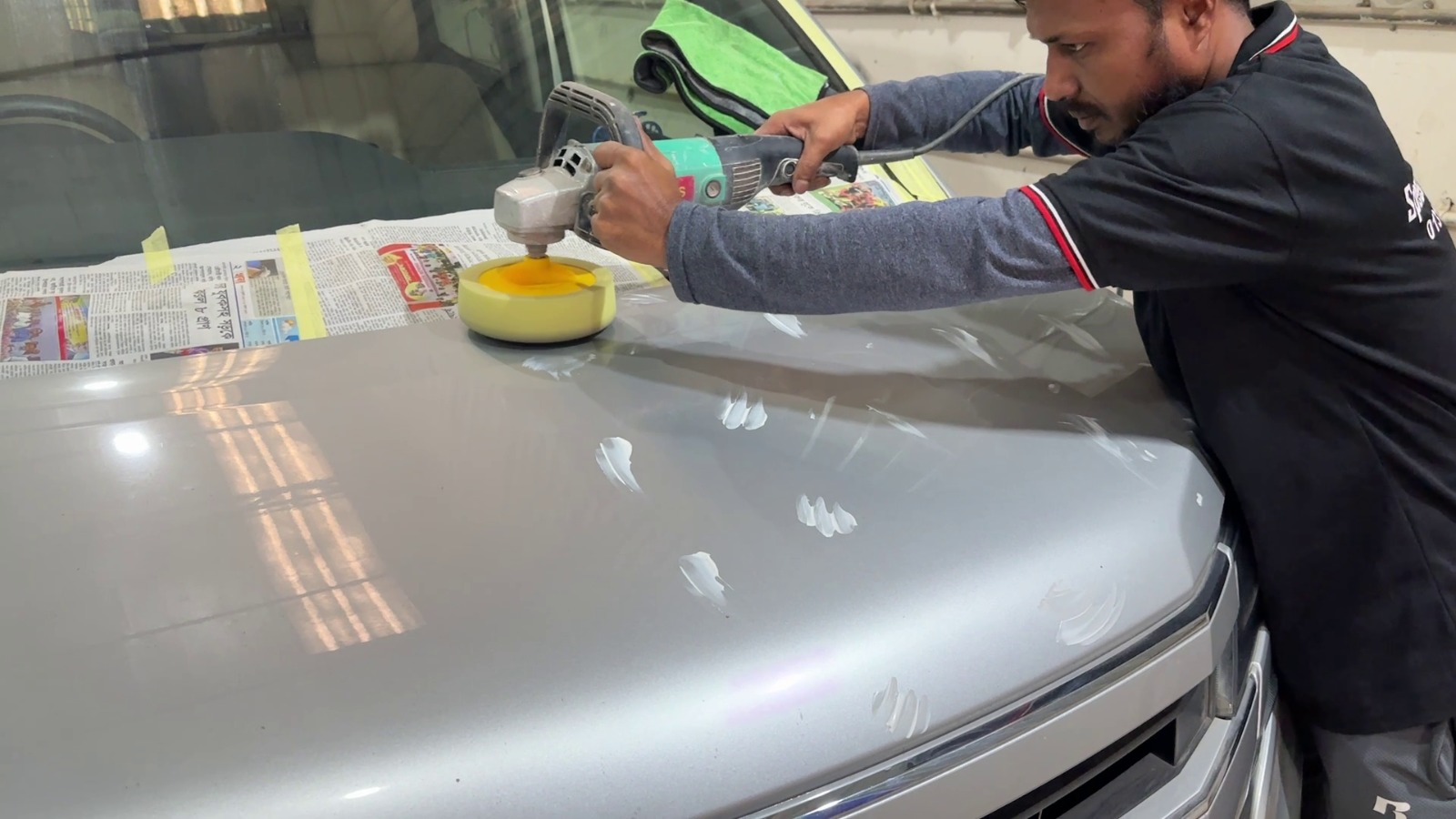 Speed Auto Care technician machine-polishing a silver car hood