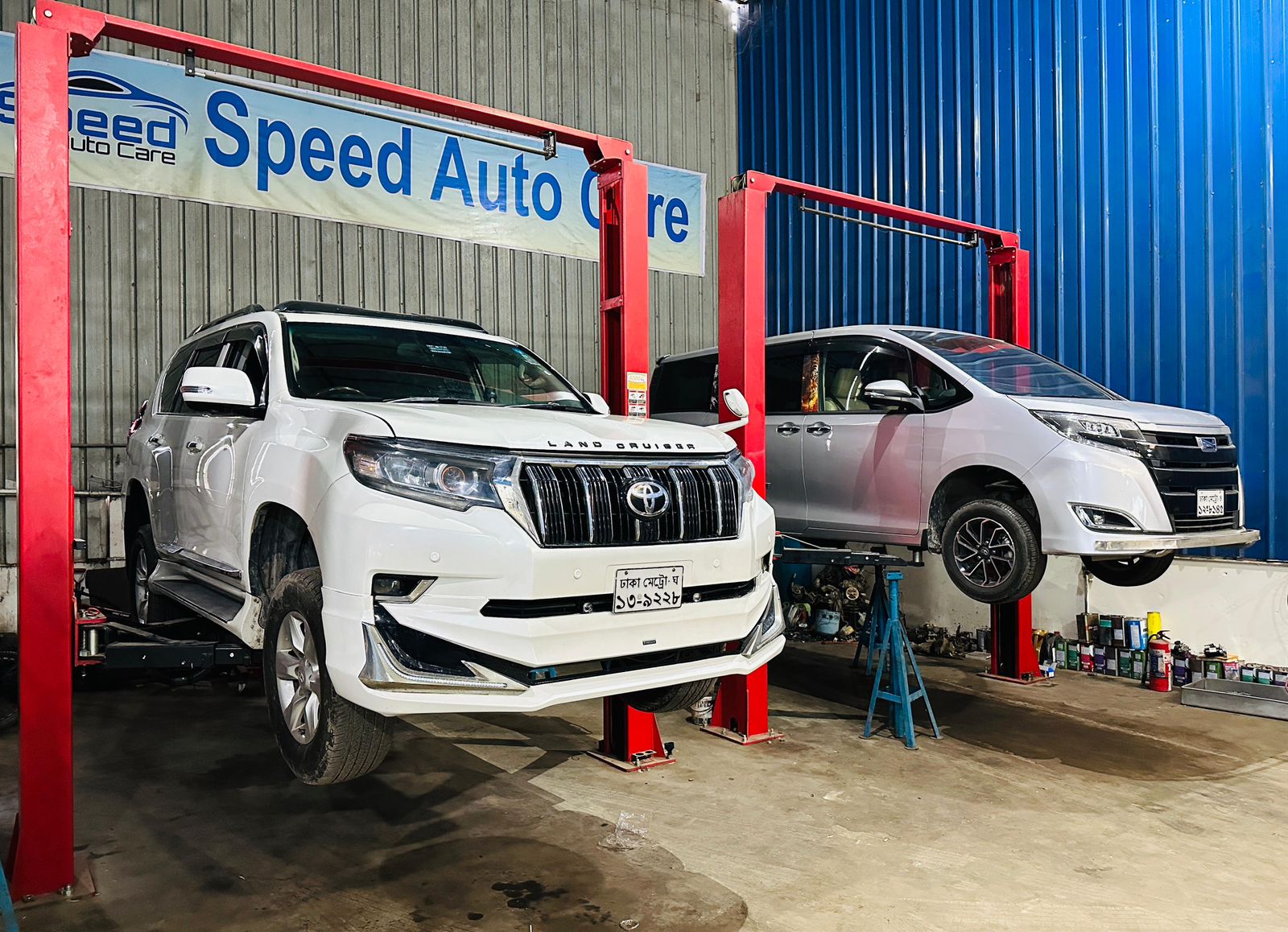 Two vehicles being serviced on lifters under the Speed Auto Care banner